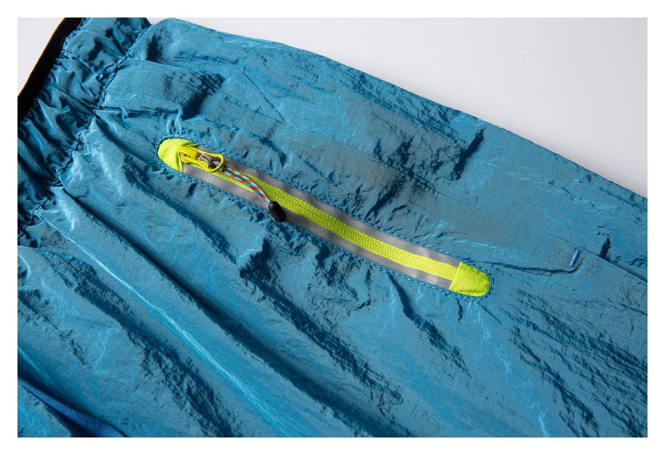 Close-up of turquoise patterned running shorts with a neon yellow zippered pocket and multicolor pull cord.