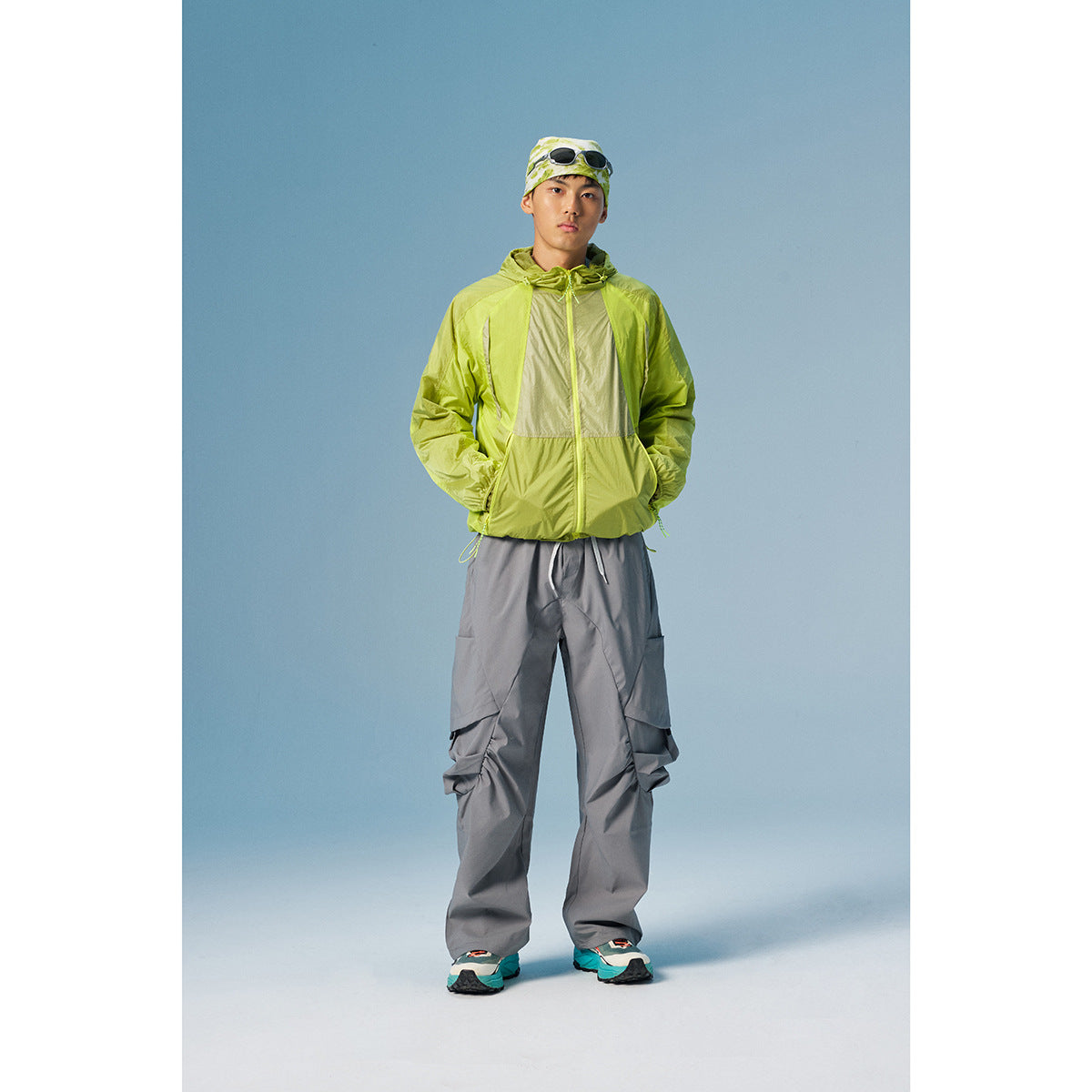 Model wearing a lime green color-block hooded jacket with loose gray cargo pants.