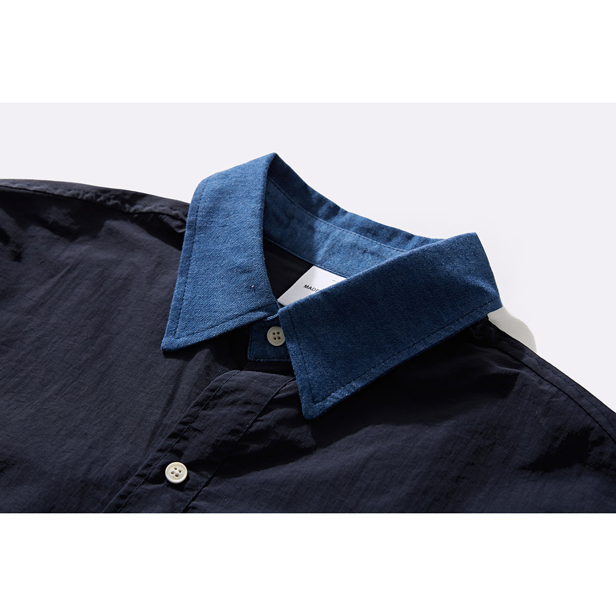 Close-up of a dark navy shirt with a contrasting blue collar and cream buttons.