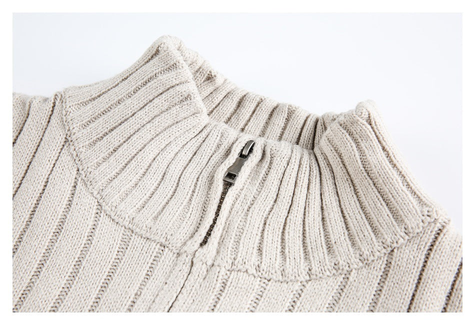 Close-up of the ivory ribbed sweater's tall collar and short metal zipper on a white background.
