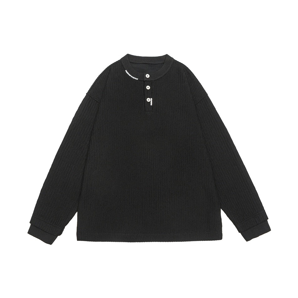 Black ribbed long-sleeve Henley top with three white buttons and small white lettering at collar, flat lay