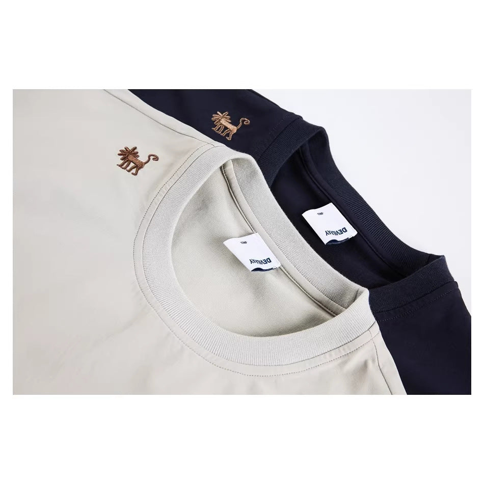 Close-up of beige and navy T-shirt necklines with ribbed collars and small embroidered animal motifs.