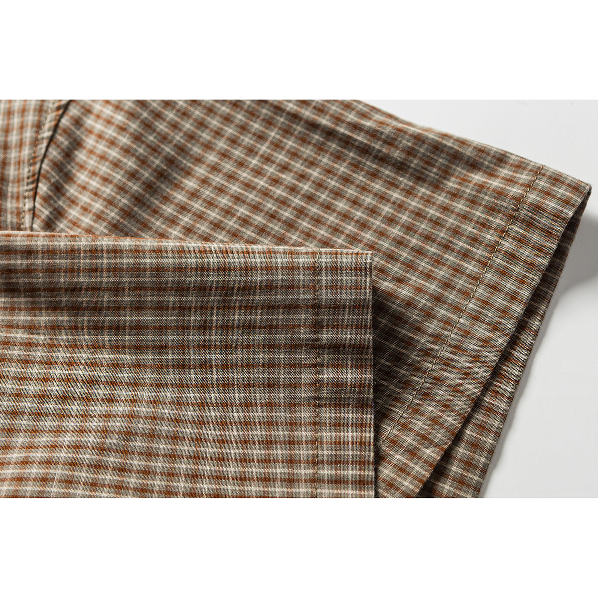 Close-up of a brown plaid shirt sleeve and cuff laid flat.