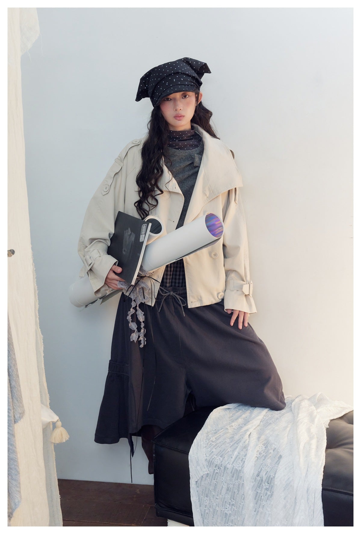 Full-length model wearing a cream oversized jacket, gray top, navy wide-leg bottoms, and a black polka-dot headscarf.