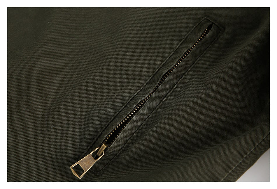 Close-up of a diagonal brass-toned zipper on the olive jacket.