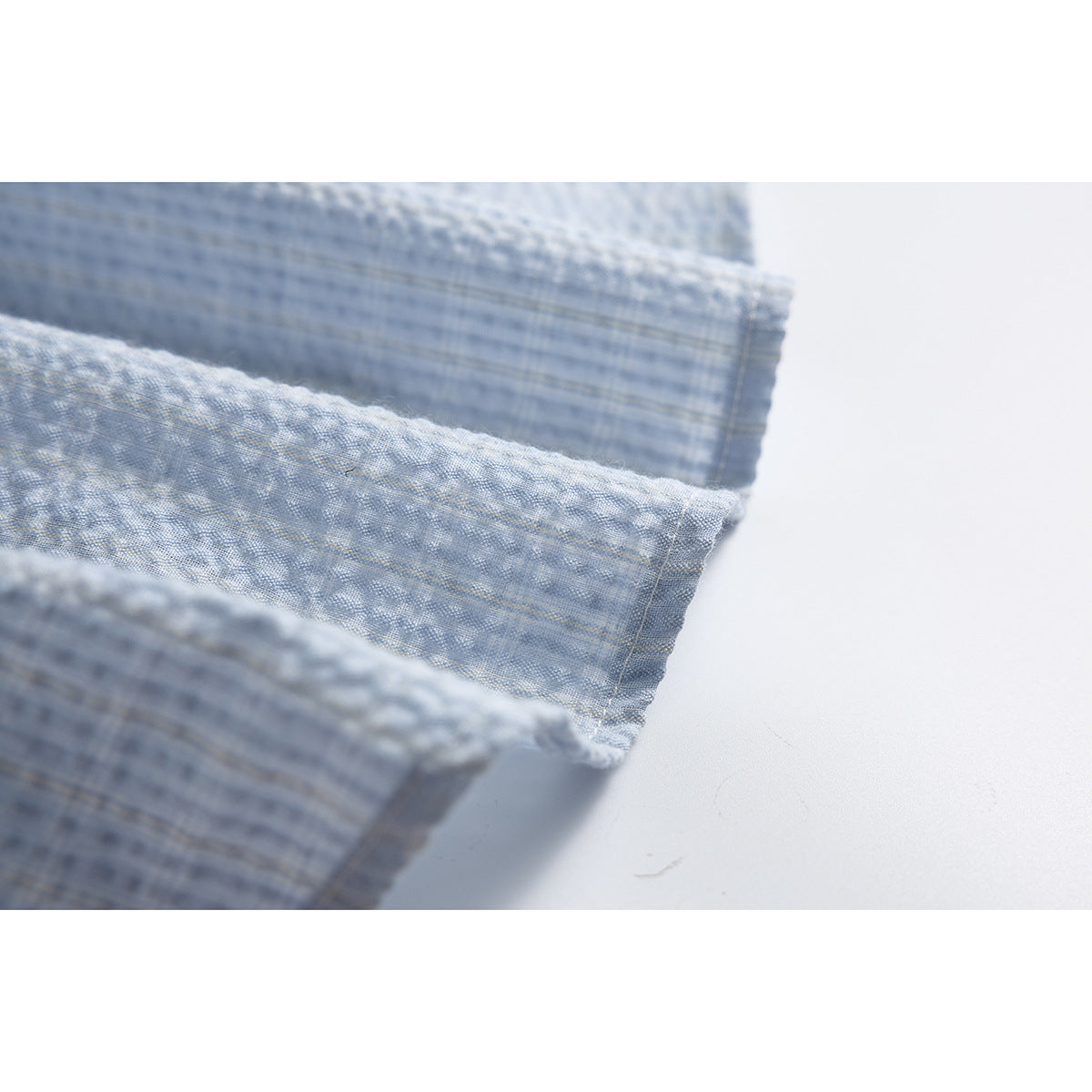 Close-up of the pale blue shirt fabric and a folded, stitched edge.