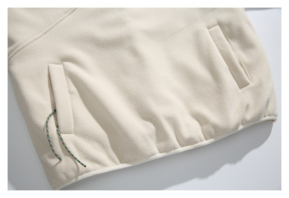Lower front of a cream garment with angled pockets and multicolored cords at the hem.