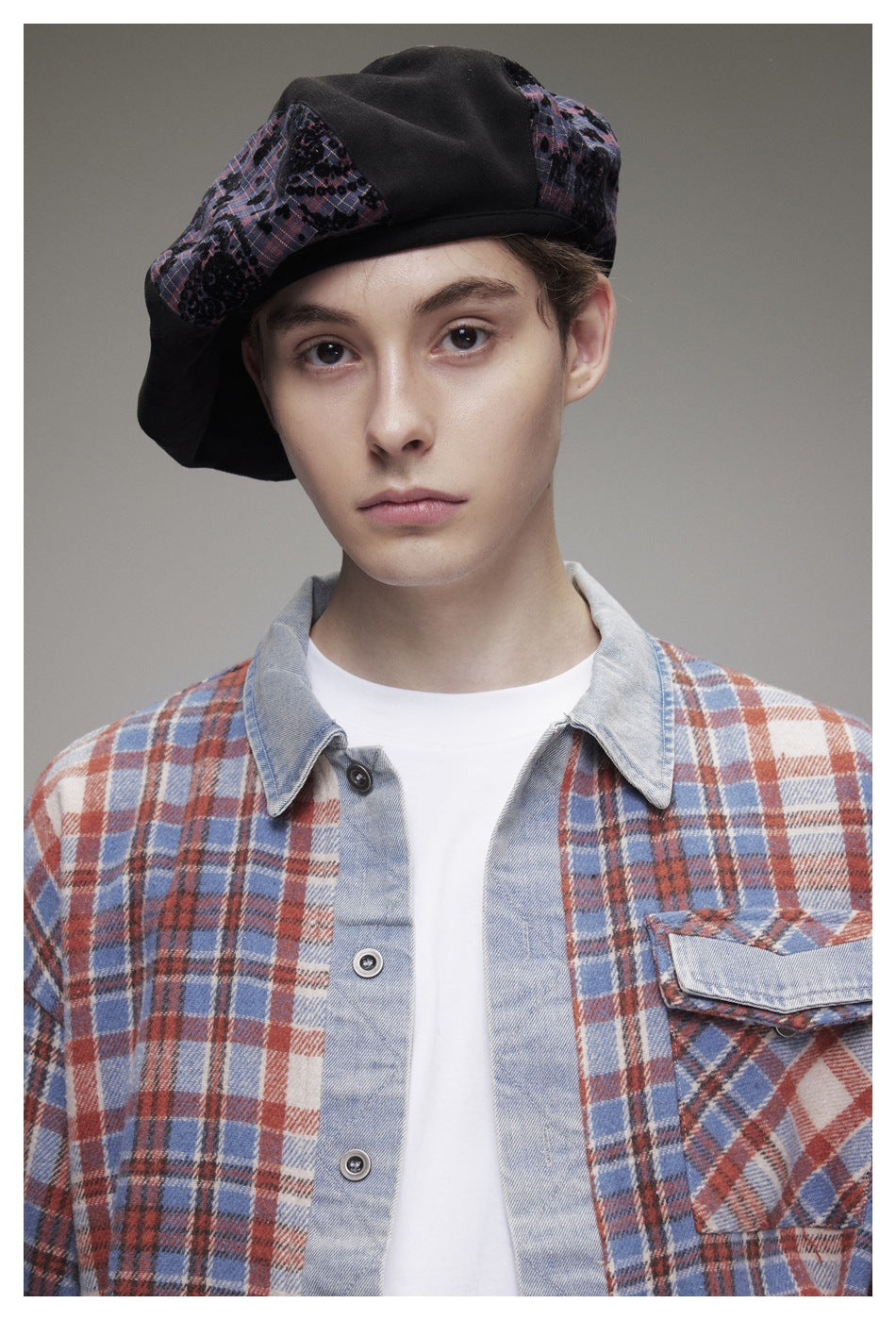 Framed portrait of a model in a blue, rust and cream plaid overshirt with a pale collar and flap chest pocket.