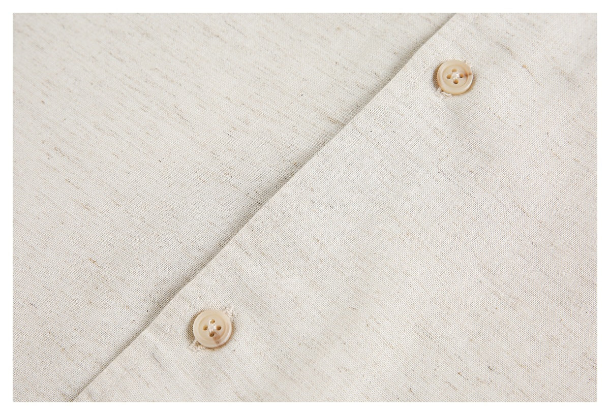 Close-up of two beige buttons on the placket of an ivory flecked garment.