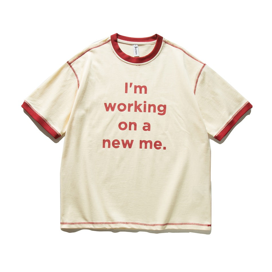 Apricot short-sleeve T-shirt with red collar, cuffs and stitching and a red "I'm working on a new me." slogan print