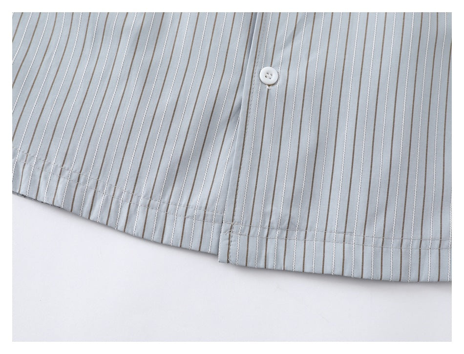 Close-up of the pale blue-gray shirt's striped lower hem and buttoned front.