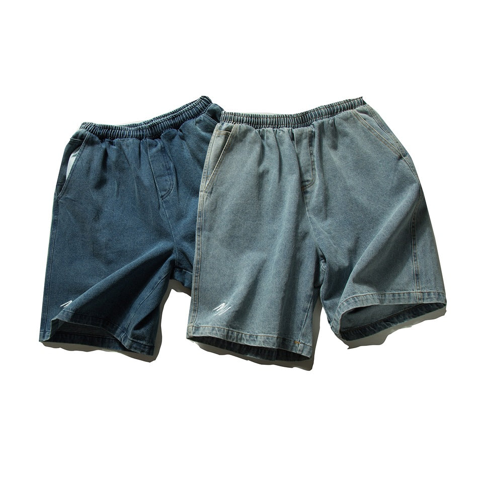 Two pairs of loose denim shorts displayed from the front in dark blue and faded blue-gray, with elastic waistbands.