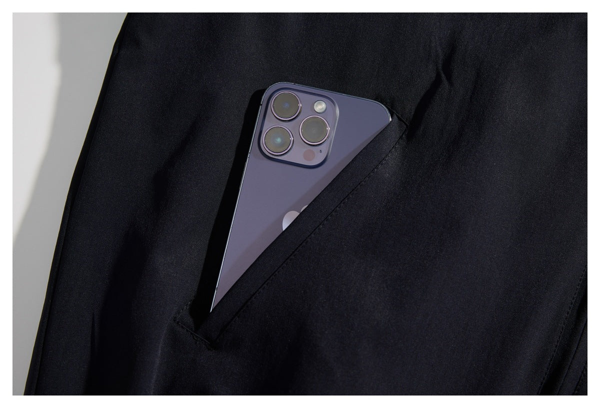 A dark garment's angled pocket holds a purple smartphone, shown in close-up.