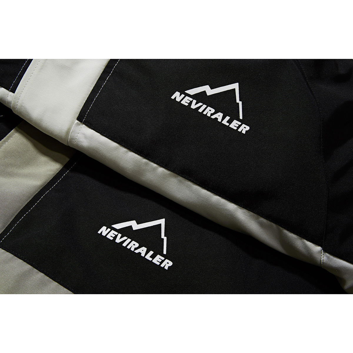 Close-up of black and light gray jacket panels with white NEVIRALER logos and visible stitching.