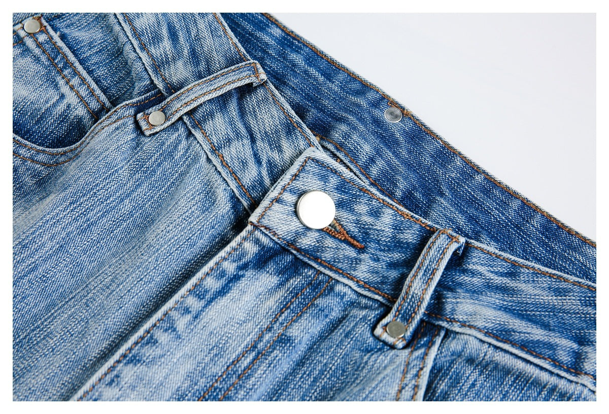 Close-up of the jeans' front button, waistband, belt loop, and faded denim.