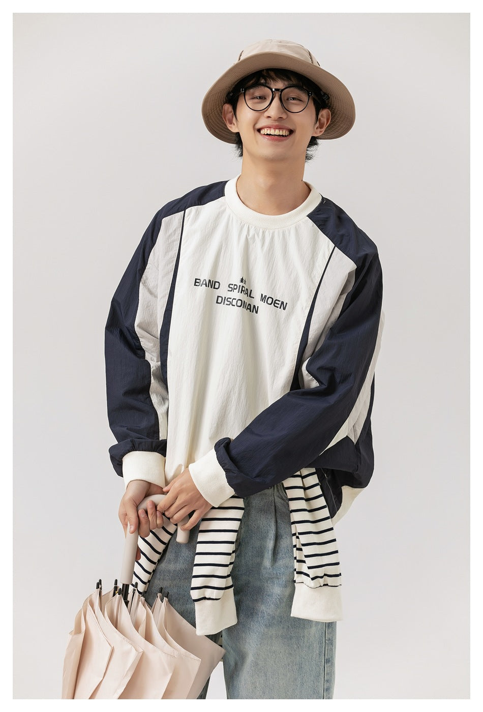Front view of a model wearing an ivory pullover with navy sleeves and black chest lettering.