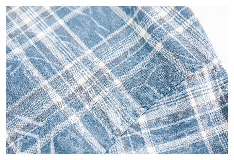 Close-up of blue and white plaid fabric showing a stitched pocket edge.