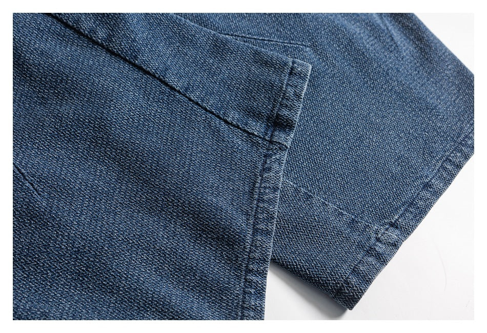 Close-up of a stitched seam and folded edge on dark blue denim trousers.
