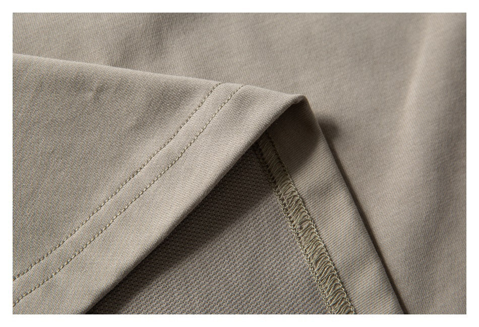 Close-up of a taupe garment hem showing double stitching and an interior overlocked seam.