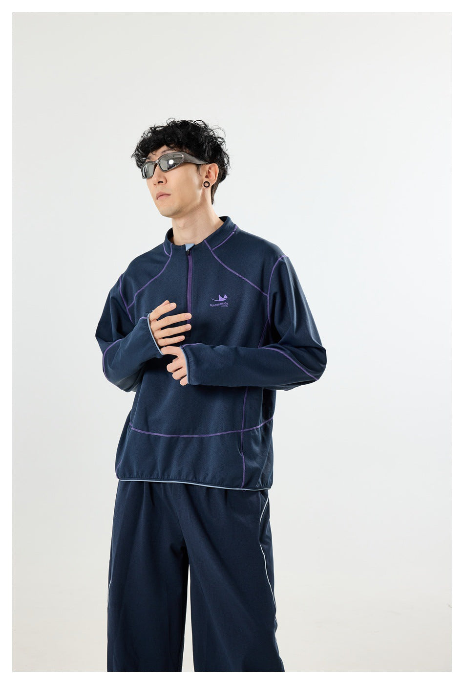 Closer view of a model wearing a navy quarter-zip pullover with purple seam detailing.