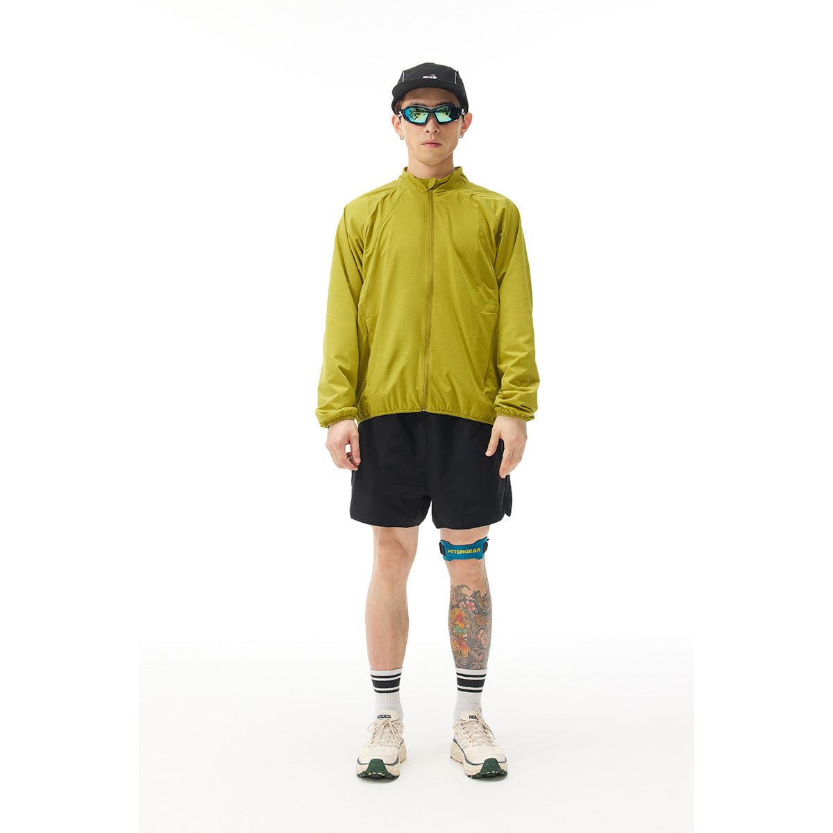 Model wearing a chartreuse zip jacket and black shorts, shown from the front.
