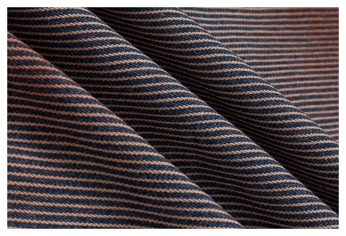 Macro view of navy and rust diagonal-striped fabric arranged in soft folds.