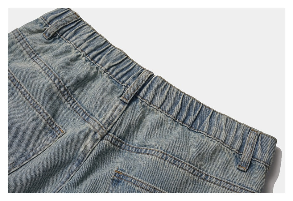 Close-up of light-wash denim trousers showing an elasticated waistband, belt loops and part of a back pocket.