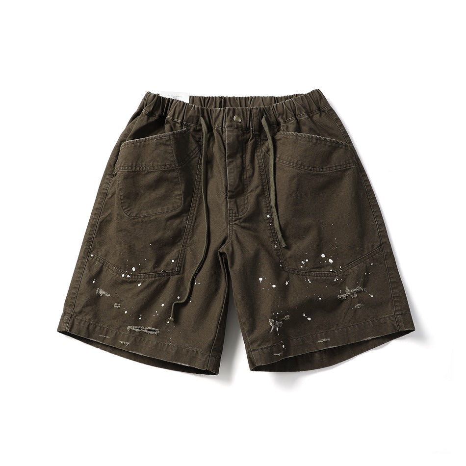 Brown knee-length shorts with elastic drawstring waist, large front patch pockets, paint splatters and frayed rips