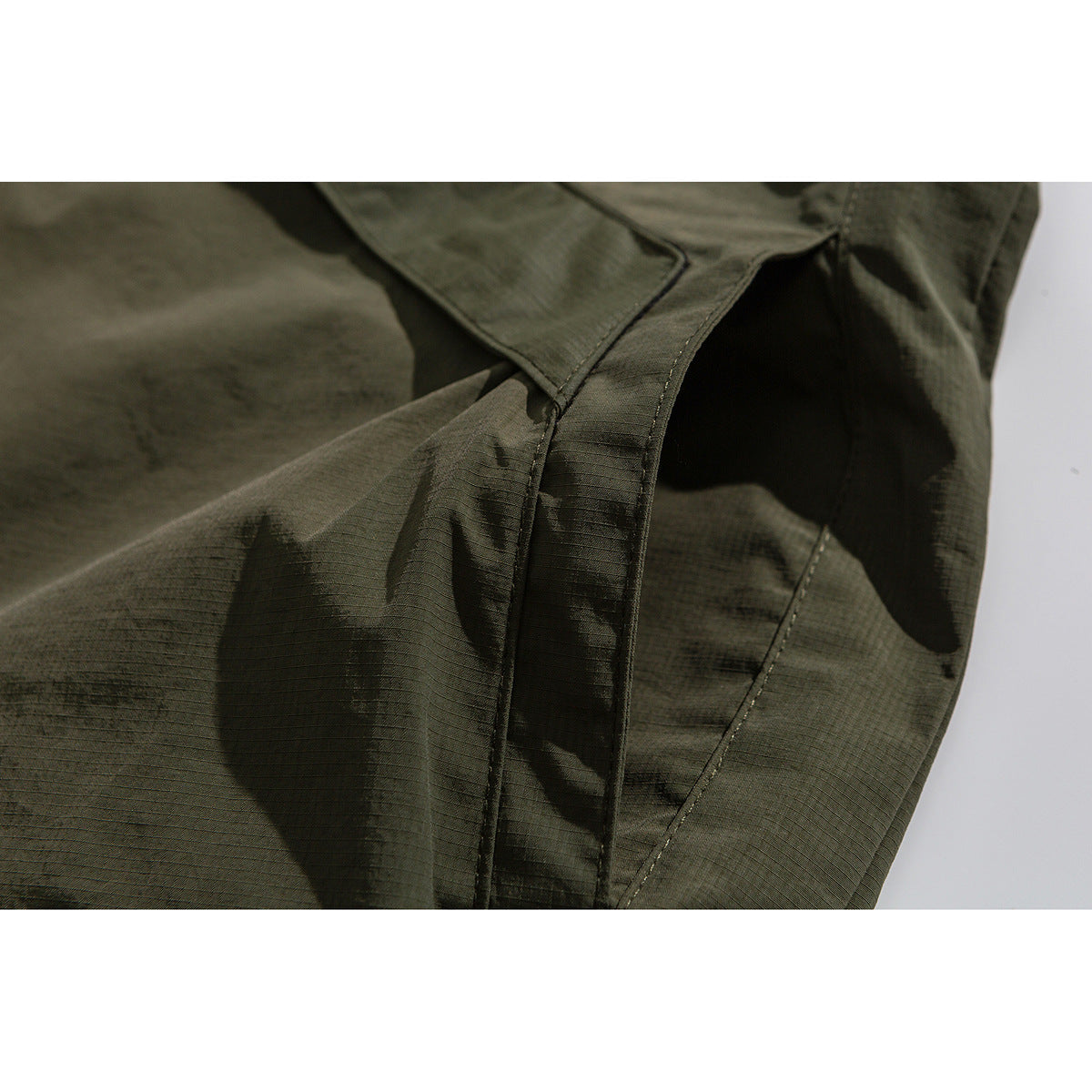 Close-up of seam and panel construction on an olive jacket.