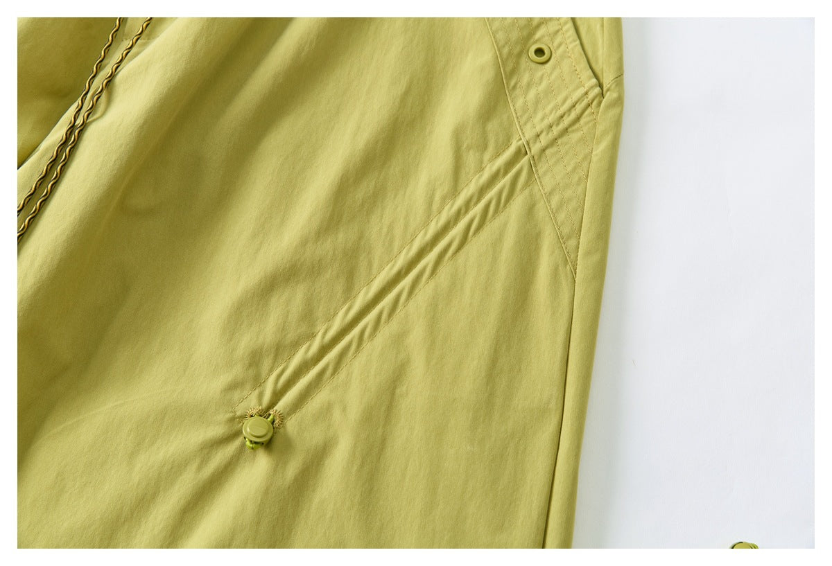 Close-up of yellow-green pants with a diagonal seam and a small adjustable side tab.