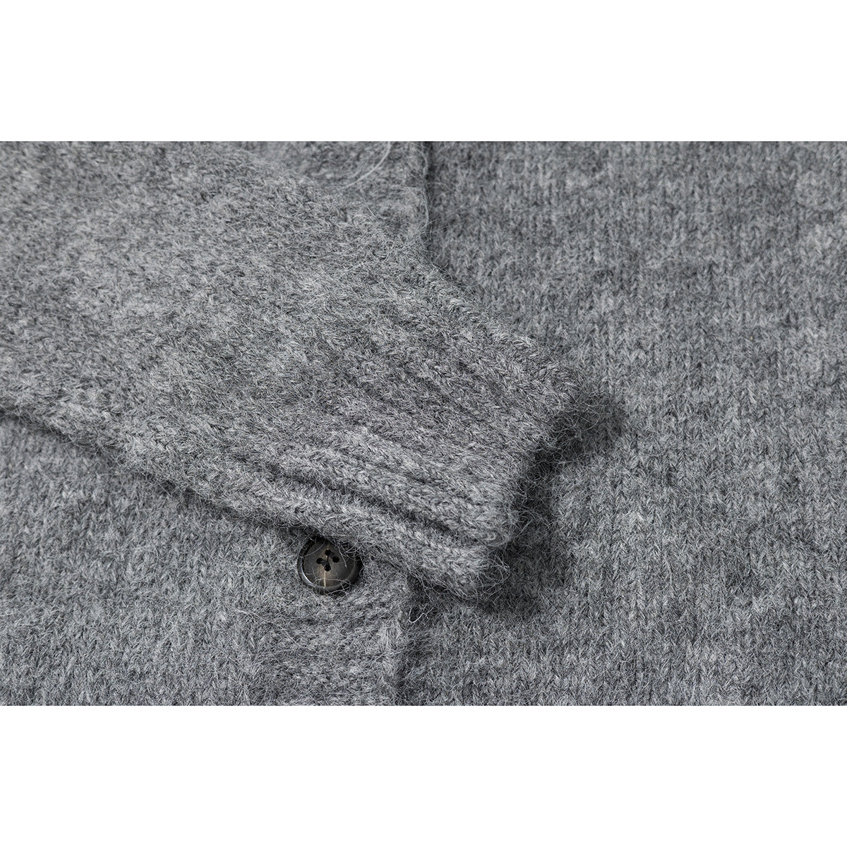 Close-up of gray cardigan knit, a folded button placket, and a dark button.