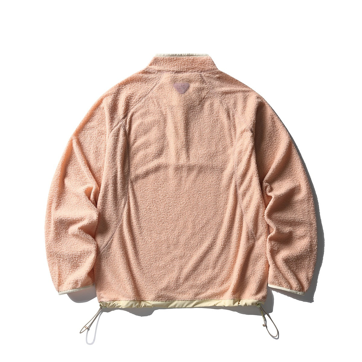Back view of a peach fleece pullover with a raised collar, curved seam lines, and adjustable hem cords.