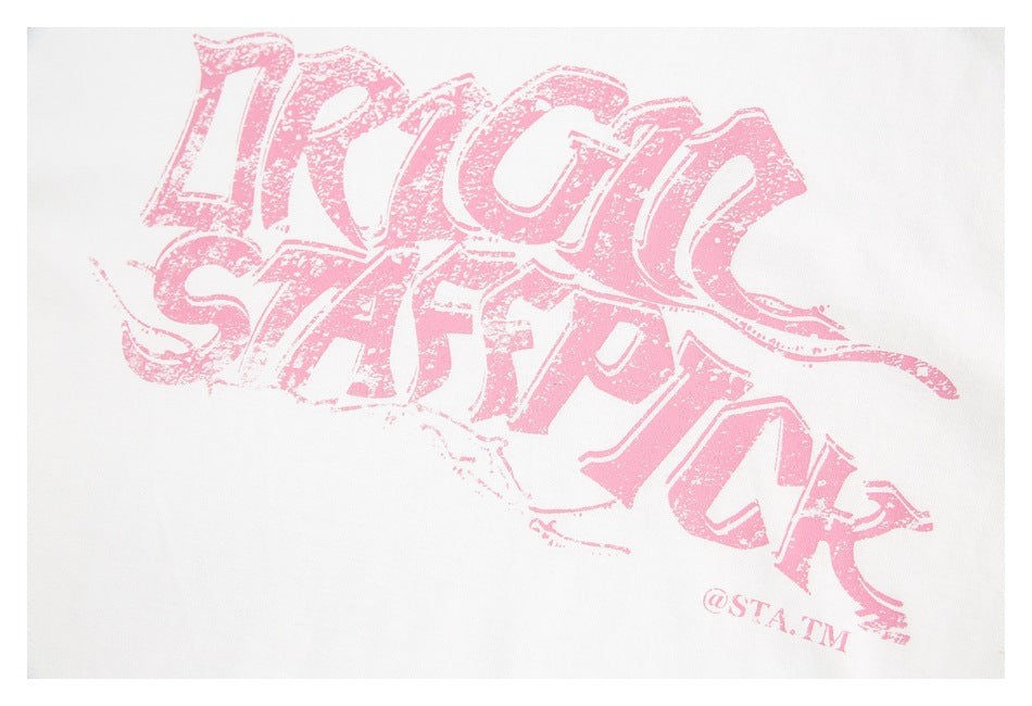 Close-up of a distressed pink lettering graphic printed on a white T-shirt.