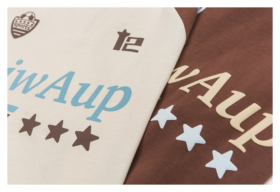 Close-up of cream and brown T-shirt chest prints, showing lettering, stars, and small emblems.