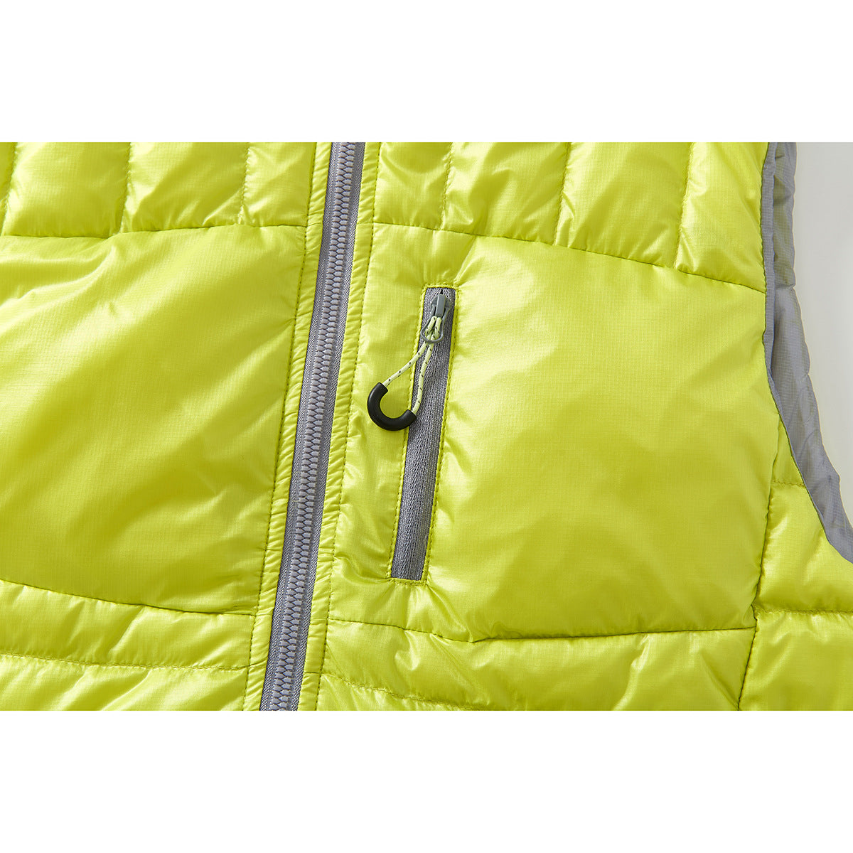 Close-up of the lime-yellow vest’s gray front zipper and vertical chest pocket with a black pull.