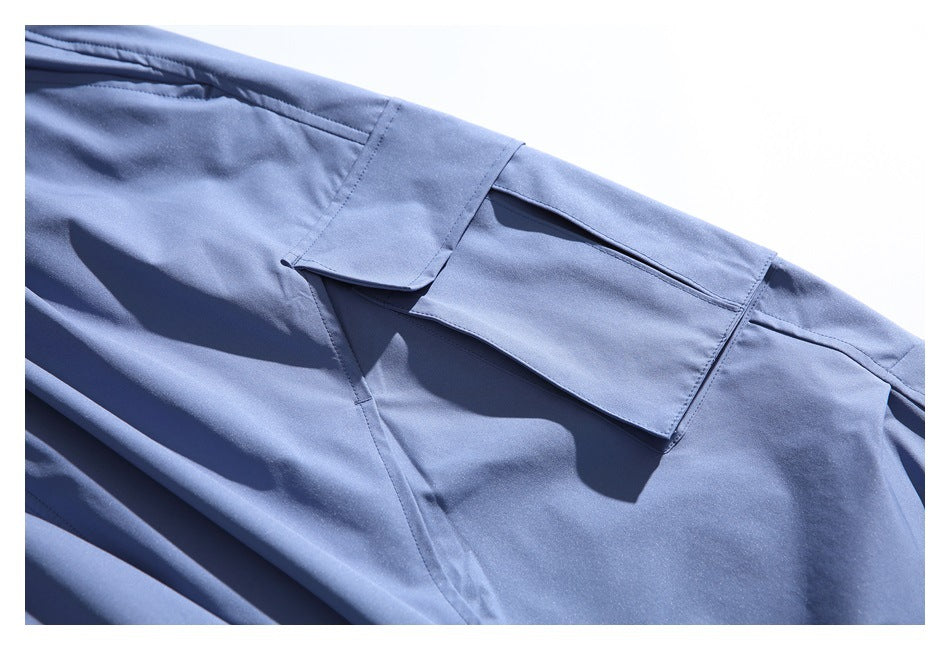 Close-up of a blue garment with a flap pocket and visible stitching.