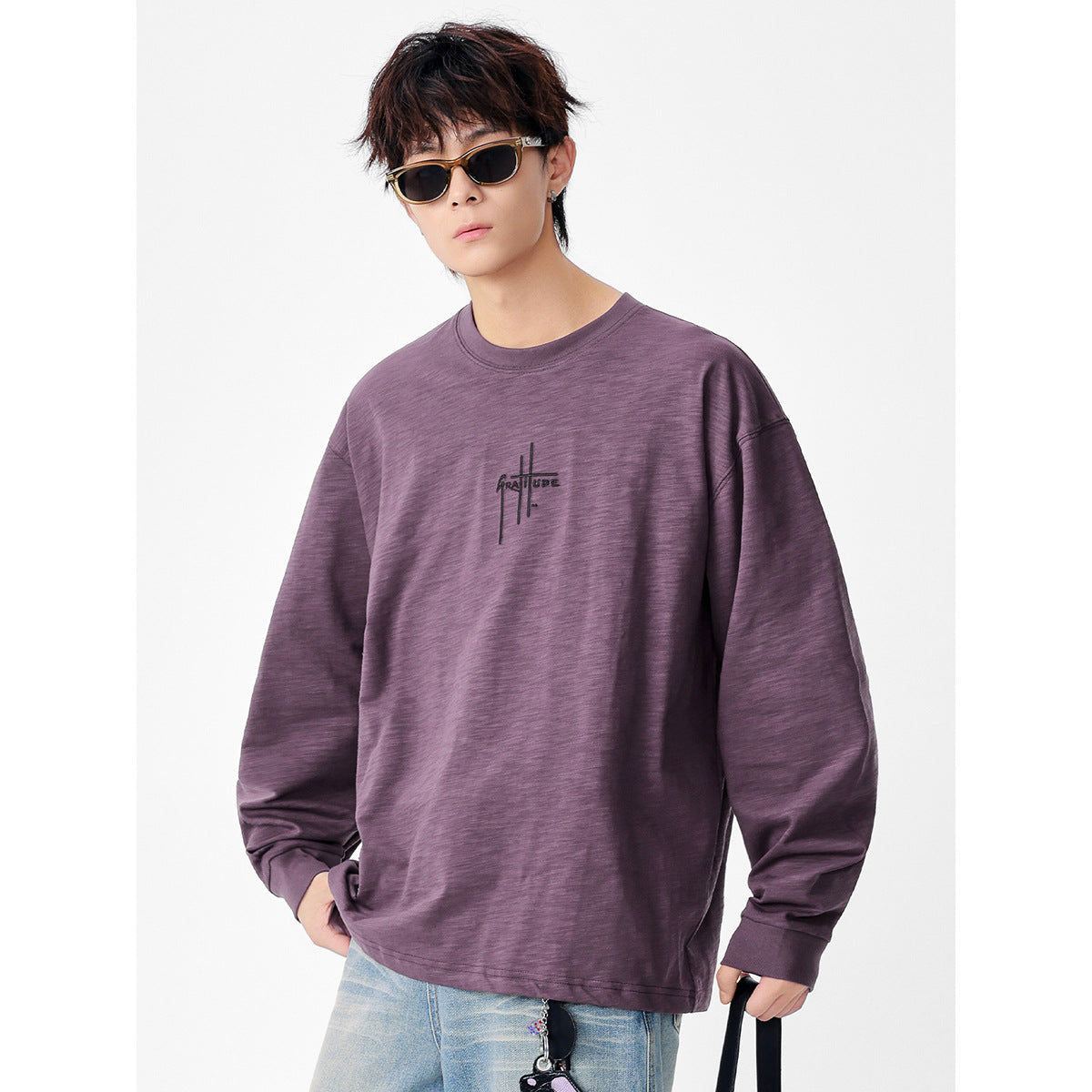 Model wearing an oversized plum long-sleeve shirt with a small black chest graphic.