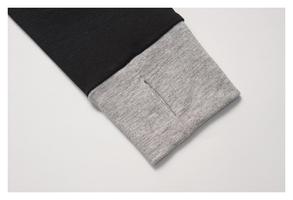 Close-up of a black sleeve with a wide heather-gray ribbed cuff.
