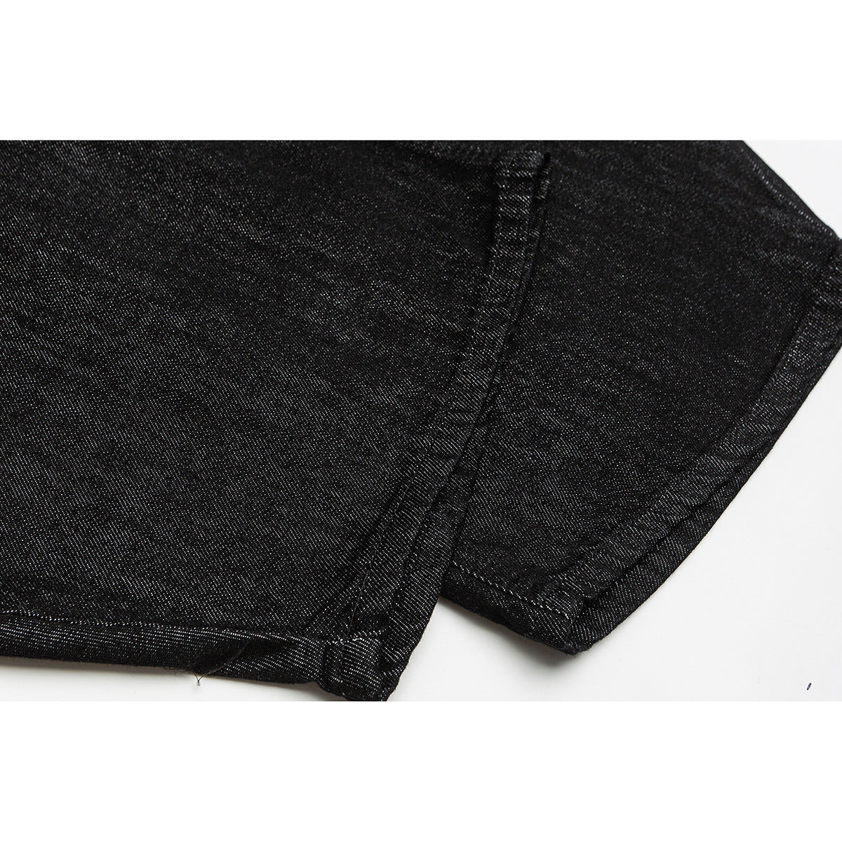 Close-up of black trouser leg fabric and stitched seams near the hem.