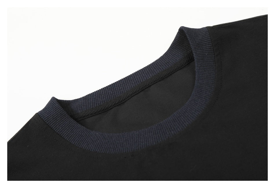 Close-up of a black T-shirt's crew neckline, finished with a dark navy ribbed collar.