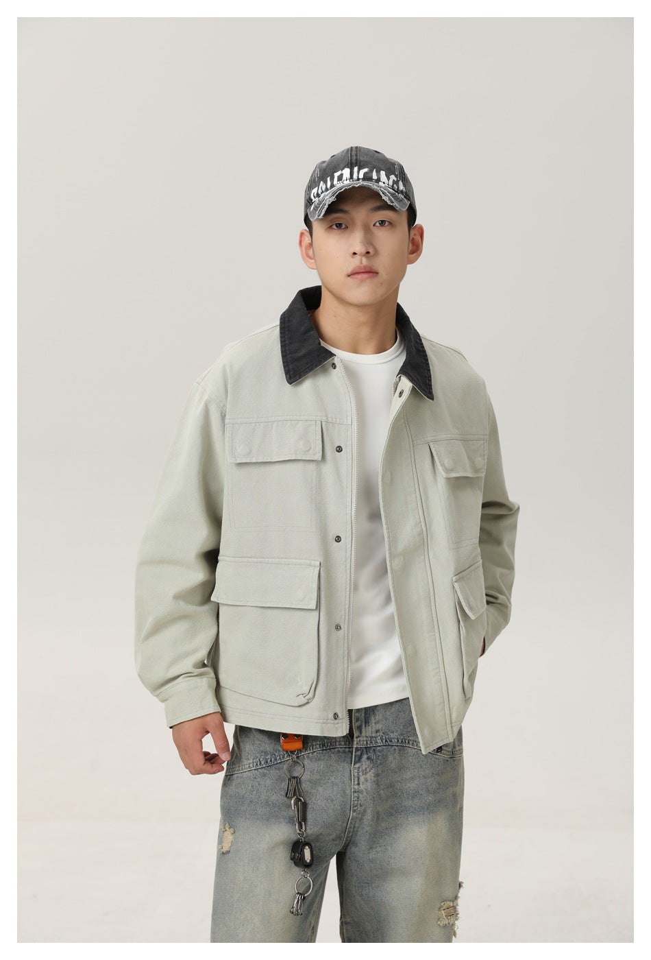 Model wearing a pale gray-green utility jacket with a dark collar, four flap pockets and front buttons.