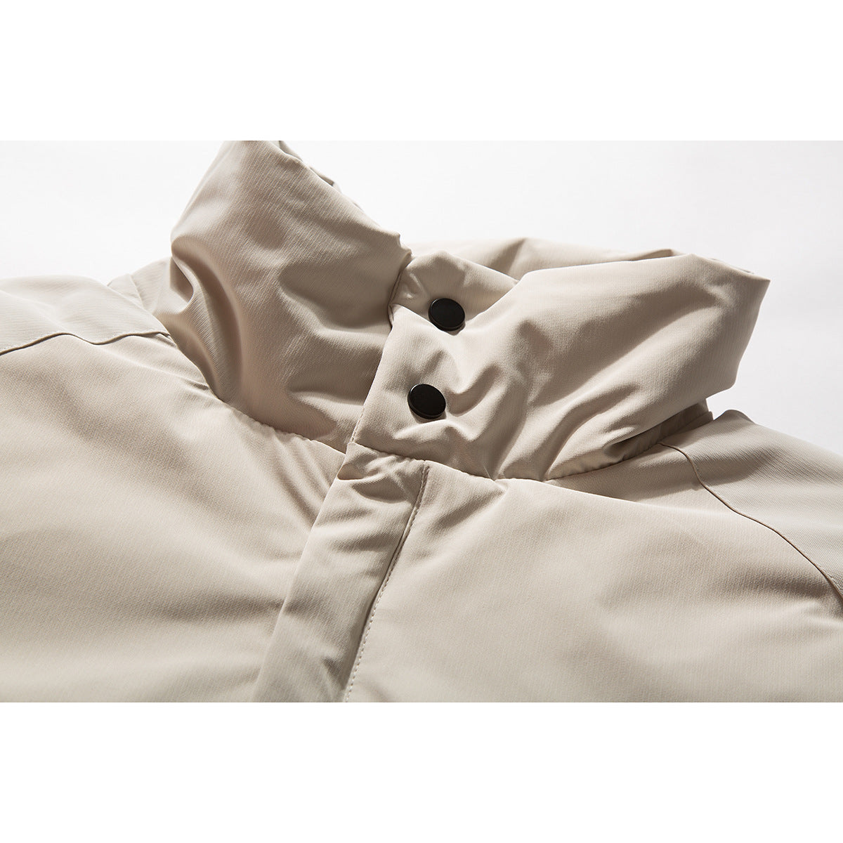 Close-up of a light beige jacket collar and front placket with two black snaps.