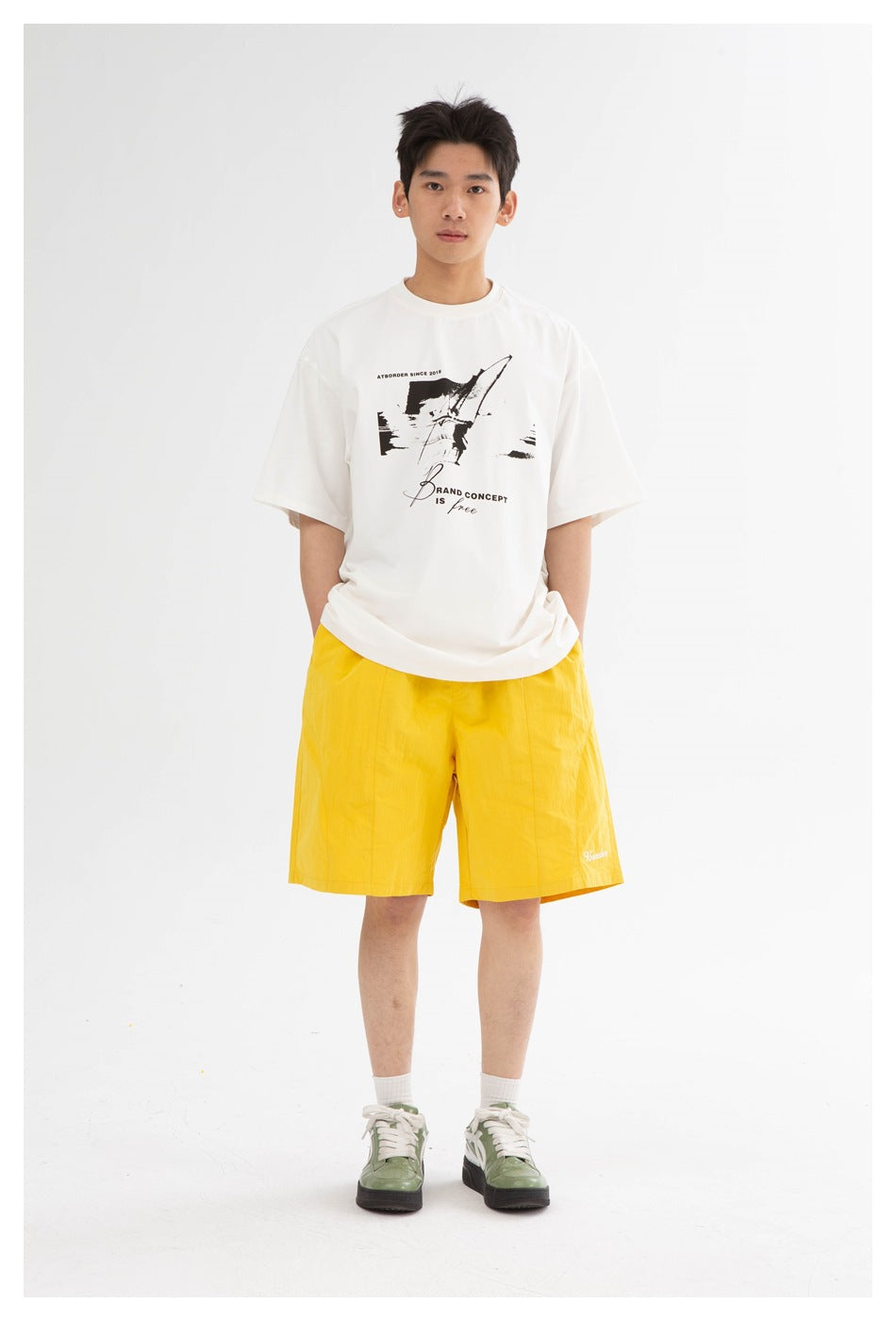 Front view of a model wearing bright yellow knee-length shorts with a white graphic T-shirt.