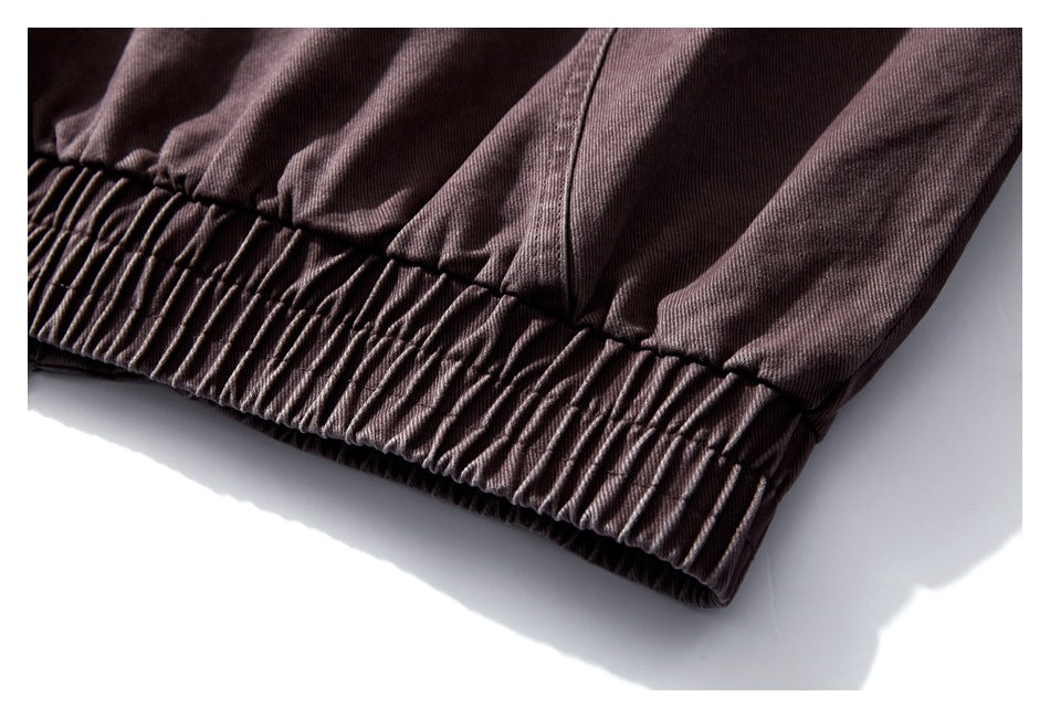 Close-up of a gathered elastic hem on dark mauve-brown pants, showing the stitching and fabric texture.