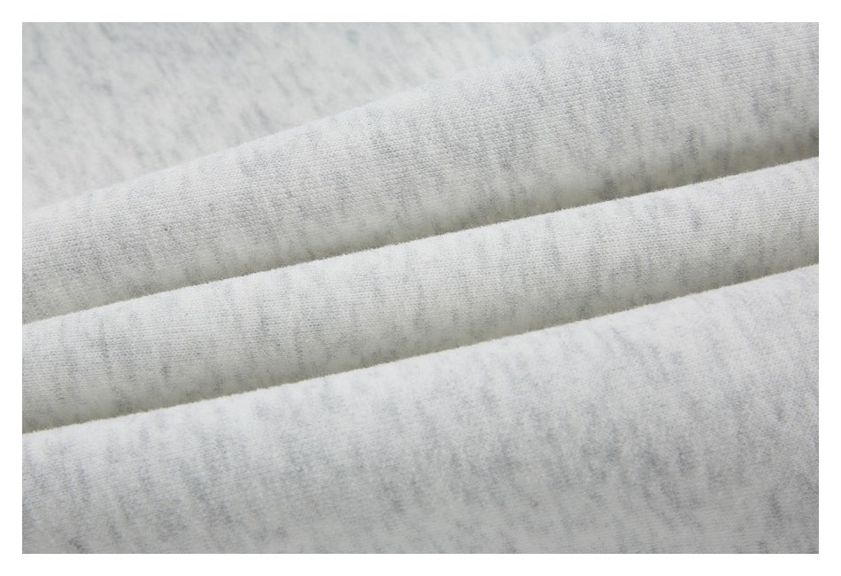 Close-up of light gray marl fabric folded into parallel ridges, showing its knit texture.