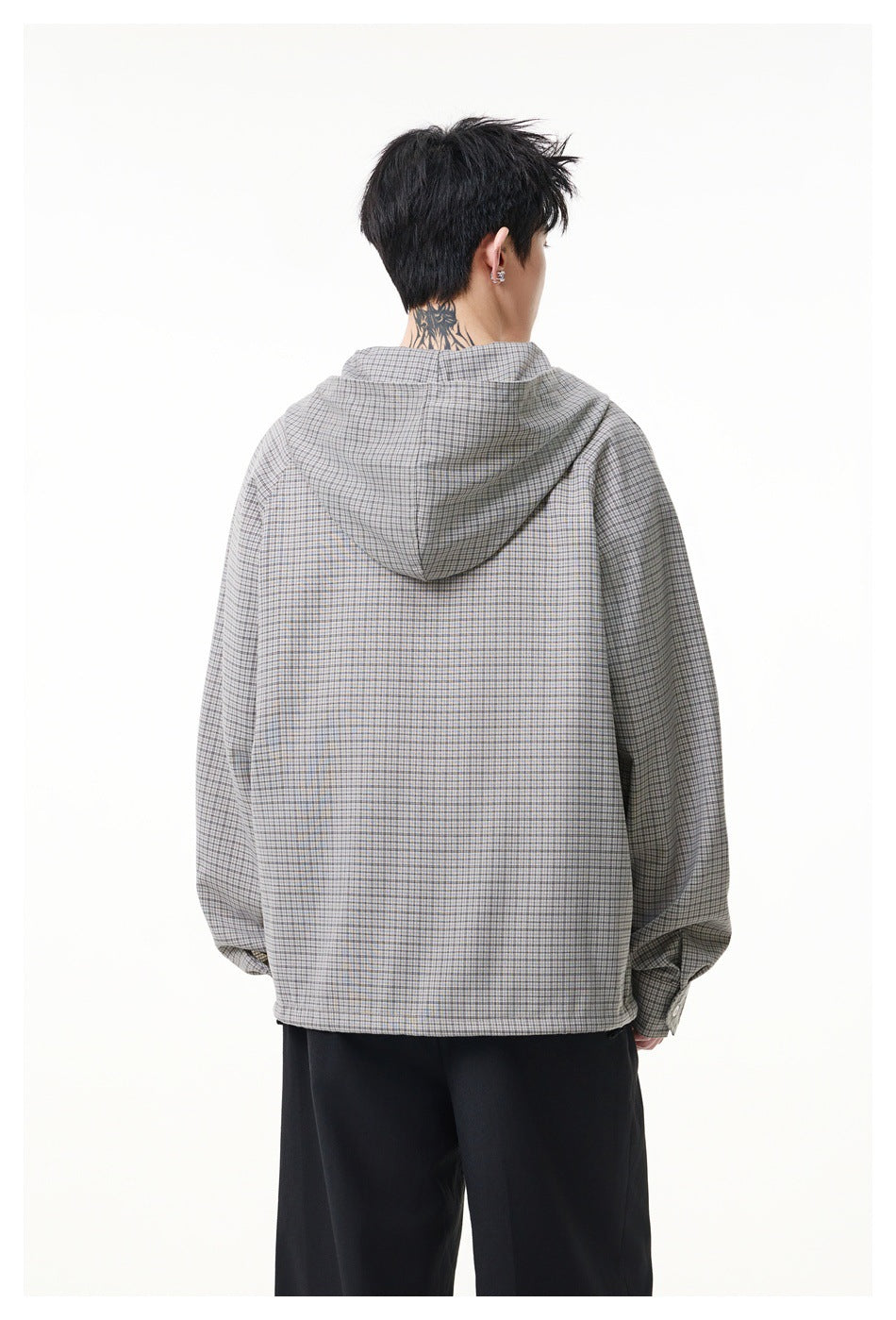 Rear view of a model wearing a gray checked hooded pullover with black trousers.