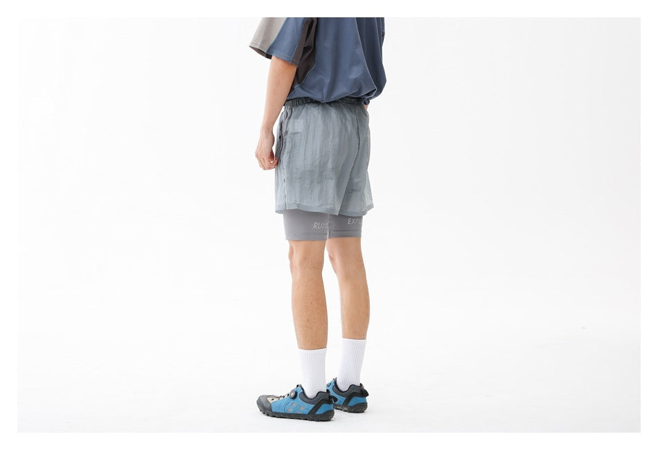 Rear-side view of a person wearing pale blue-gray running shorts over gray compression shorts.