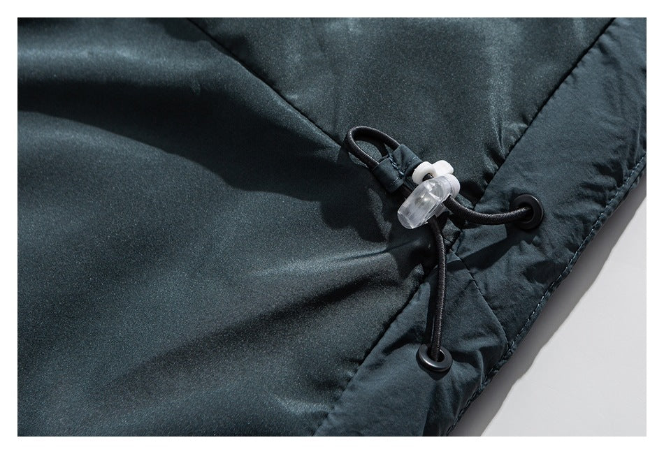 Close-up of a dark garment edge with an elastic drawcord, plastic toggle and reinforced eyelets.