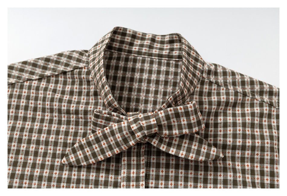 Close-up of a brown, white, and rust plaid shirt collar and matching bow tie.
