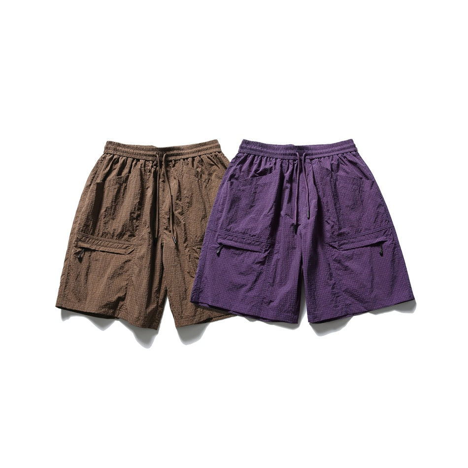 Front view of brown and purple check shorts displayed side by side, with elastic waists and flap pockets.
